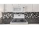 Close-up of kitchen with tile backsplash, stovetop, and white cabinetry at 13408 W Mauna Loa Ln, Surprise, AZ 85379