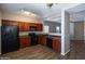 A kitchen featuring black appliances, cherry cabinets, and wood-look floors at 18474 N Celis St, Maricopa, AZ 85138