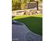 Tranquil backyard with artificial grass, decorative waterfall feature, desert landscaping, brick patio and fruit tree at 32071 N Chestnut Trl, San Tan Valley, AZ 85143