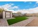 Backyard featuring artificial turf, a shed, and a low rock wall at 3530 N 310Th Dr, Buckeye, AZ 85396