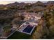 Stunning aerial view of a luxury home with pool, lush landscaping, and mountain backdrop at dusk at 3977 E Paradise View Dr, Paradise Valley, AZ 85253