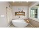 Bright bathroom with a white soaking tub, wood accents, decorative macrame, and a large window at 3977 E Paradise View Dr, Paradise Valley, AZ 85253