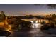 Elegant home with a circular driveway, manicured landscaping, and stunning city views at dusk at 3977 E Paradise View Dr, Paradise Valley, AZ 85253