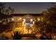 Well-lit home exterior with an arched entryway and desert landscaping at night at 3977 E Paradise View Dr, Paradise Valley, AZ 85253