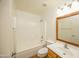 Bright bathroom featuring a tub with shower, toilet and vanity with a wood trimmed mirror at 43639 W Blazen Trl, Maricopa, AZ 85138