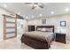 Spacious primary bedroom with sliding barn door to ensuite bathroom, neutral colors and dark furniture set on tile floor at 4502 E Hartford Ave, Phoenix, AZ 85032