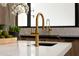 Close up of a gold faucet on a white countertop with light wood cabinets and black trimmed window in the background at 7014 E Palo Verde Ln, Paradise Valley, AZ 85253
