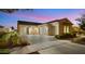 Charming home exterior featuring a three-car garage and desert landscaping at twilight at 10455 E Thatcher Ave, Mesa, AZ 85212