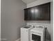This laundry room features a modern washer and dryer with sleek cabinets above at 10455 E Thatcher Ave, Mesa, AZ 85212