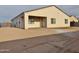 View of the home's stucco back exterior featuring a covered patio with tiled floor, and a spacious, unfinished backyard at 1586 N Himosa Dr, Casa Grande, AZ 85122