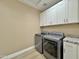 Functional laundry room features a washer and dryer set, gray tiling, and white cabinets at 1586 N Himosa Dr, Casa Grande, AZ 85122