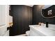 Unique powder room featuring a black textured wall, white vanity, and brass fixtures at 17414 N 56Th Way, Scottsdale, AZ 85254