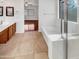 Bright bathroom featuring a tub and vanity with hardwood cabinets, tile floors and lots of light at 17649 W Young St, Surprise, AZ 85388