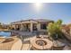Beautiful backyard featuring fire pit, pool, covered patio, and well-maintained landscaping at 18215 N Shadow Ct, Surprise, AZ 85374