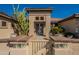 Close-up view of the charming stucco front entrance featuring a decorative gate and desert landscaping at 18215 N Shadow Ct, Surprise, AZ 85374