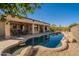 Stunning backyard featuring a custom pool with rock accents, lush desert landscaping, and a covered patio at 18215 N Shadow Ct, Surprise, AZ 85374