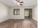 Bright, vacant room with a ceiling fan, modern wood-style flooring, and a sliding glass door to backyard at 21198 W Berkeley Rd, Buckeye, AZ 85396