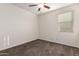 A simple carpeted bedroom with a ceiling fan and a sun-drenched window at 21198 W Berkeley Rd, Buckeye, AZ 85396