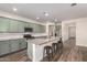 Spacious kitchen with stainless steel appliances, granite countertops, a kitchen island, and stylish light green cabinets at 21198 W Berkeley Rd, Buckeye, AZ 85396