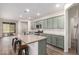 Open concept kitchen with a large island, granite countertops, modern appliances, and stylish, light green cabinets at 21198 W Berkeley Rd, Buckeye, AZ 85396