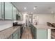 Contemporary kitchen with light green cabinets, granite countertops, stainless steel appliances, and tile backsplash at 21198 W Berkeley Rd, Buckeye, AZ 85396