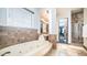 Inviting bathroom featuring a large soaking tub, walk-in shower, and travertine tile at 2330 N Channing --, Mesa, AZ 85207