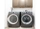 Well-lit laundry room featuring modern front-loading washer and dryer units, complemented by sleek cabinetry at 3726 S Juniper St, Tempe, AZ 85282