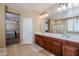 Bathroom featuring dual sinks, wood cabinetry, and access to the primary bedroom at 5110 W Sweet Iron Pass, Phoenix, AZ 85083