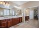 Well-lit bathroom with dual sinks, wood cabinetry, and mirrored closet, offering a blend of style and functionality at 5110 W Sweet Iron Pass, Phoenix, AZ 85083
