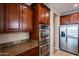 Modern kitchen with stainless steel appliances, wooden cabinets, granite countertops, and tile floors at 5110 W Sweet Iron Pass, Phoenix, AZ 85083