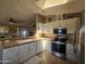 Updated kitchen featuring white cabinets, stainless steel appliances, and tiled floors with bar to living area at 650 N Hawes Rd # 4834, Mesa, AZ 85207