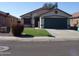 Charming single-Gathering home featuring a two-car garage and a well-maintained front yard with green grass and a decorative bush at 13819 W Berridge Ln, Litchfield Park, AZ 85340