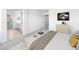 A staged bedroom with neutral decor, a king-size bed, soft carpet, and an adjacent bathroom with white cabinets at 14634 W Sand Hills Rd, Surprise, AZ 85387