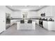 A modern kitchen features white cabinets, stainless steel appliances, granite counters, and a gray tile floor at 14634 W Sand Hills Rd, Surprise, AZ 85387