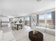 A bright living room features large windows, white sofas, a dining table and access to the backyard at 14634 W Sand Hills Rd, Surprise, AZ 85387
