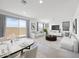 A modern living room with large windows, white sofas, modern decor, and a dining area adjacent to the living room at 14634 W Sand Hills Rd, Surprise, AZ 85387