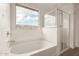 A luxurious soaking tub next to a glass-enclosed shower with a view from the bathroom window at 18433 W Monte Lindo Ln, Surprise, AZ 85387