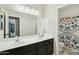 An en-suite bathroom featuring a double sink vanity with dark cabinets and a shower-tub combination at 2032 E Sierra Madre Ave, Gilbert, AZ 85296