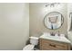 Cozy powder room features a round mirror, wood cabinet and quartz countertop at 2032 E Sierra Madre Ave, Gilbert, AZ 85296