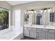 Well-lit primary bathroom with double sinks, vanity, and large window above the soaking tub at 26 S Tiago Dr, Gilbert, AZ 85233
