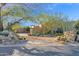 A desert landscape welcomes you to this home with mature trees, cacti, and stone accents, with a circular driveway at 34460 N 79Th Way, Scottsdale, AZ 85266