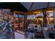An elegant outdoor living space featuring plush seating, a stone fireplace, and a full bar under a shaded awning at 34460 N 79Th Way, Scottsdale, AZ 85266