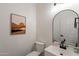 A half bath featuring an arch mirror, modern vanity, and desert-themed art at 3706 E Ravenswood Dr, Gilbert, AZ 85298