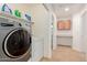 Well-organized laundry room with washer, dryer, overhead shelving, and storage space at 37379 W Amalfi Ave, Maricopa, AZ 85138