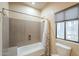 Bathroom features a shower-tub combo with a window providing natural light and neutral wall and floor tiling at 38820 N 10Th St, Phoenix, AZ 85086