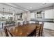 A spacious dining room showcases an expansive table, complemented by a kitchen with white cabinets, stainless appliances, and bar seating at 3930 E Enrose St, Mesa, AZ 85205