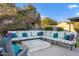 Backyard seating area with a stone fire pit and a large sectional sofa with colorful pillows at 3930 E Enrose St, Mesa, AZ 85205