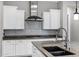 A well-appointed kitchen showcases sleek stainless steel appliances, white cabinetry, a mosaic backsplash, and a practical, functional design at 3930 E Enrose St, Mesa, AZ 85205