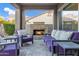 Relaxing outdoor living space with a stone fireplace, comfortable purple lounge seating, and views to the backyard at 3930 E Enrose St, Mesa, AZ 85205