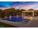Inviting backyard pool with a raised spa, fire bowls, and pergola with ambient lighting for evening relaxation at 3930 E Enrose St, Mesa, AZ 85205